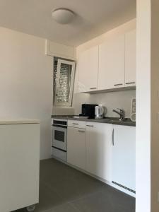 una cocina blanca con armarios blancos y fregadero en Muralto-Locarno: Miramonti Apt. 17 en Locarno