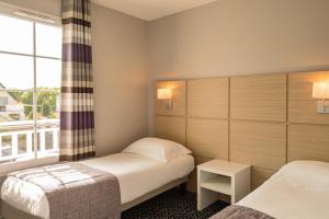 um quarto de hotel com duas camas e uma janela em Les Villas du SPA em Pléneuf-Val-André
