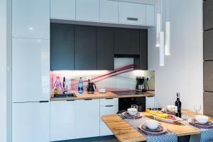 a kitchen with black and white cabinets and a table at Apartament36-1c Calamo Park in Olsztyn