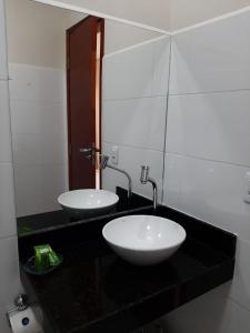 two sinks on a black counter in a bathroom at Flats Premium Jabaquara in Paraty