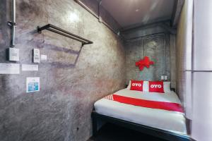 a small room with a bed with two red pillows at Super OYO 75332 Vm1 Hostel in Bangkok