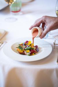 a person pouring sauce onto a plate of food at Le Meurice – Dorchester Collection in Paris