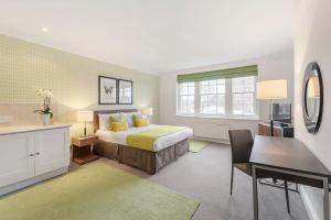 a bedroom with a bed and a desk and a table at Chelsea - Draycott Place by Viridian Apartments in London