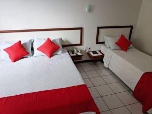 two beds in a room with red pillows at Hotel Portal De Eunápolis in Eunápolis