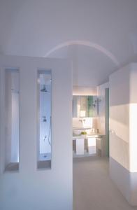 La salle de bains blanche est pourvue d'un lavabo et d'un miroir. dans l'établissement Luxury Santorini Villa Villa Pori Blanca Master Suite Private Pool and Stunning Sea View Near Pori Beach, à Foinikiá