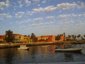 dos barcos en un cuerpo de agua con edificios en Chez Eric en Gorée