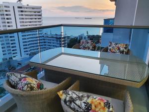 a balcony with chairs and a glass table on a building at Beachfront Family Escape 3BR Samaria Club de Playa in Gaira