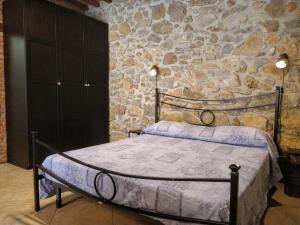 1 dormitorio con cama y pared de piedra en Casa Vanessa en Suvereto