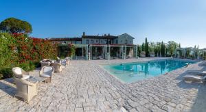 a swimming pool with chairs and a house in the background at Relais Sassa al Sole in San Miniato