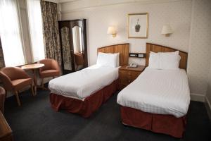 a hotel room with two beds and a table and chairs at Crown & Mitre Hotel in Carlisle