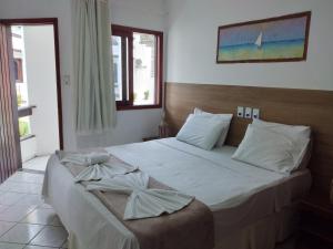 1 dormitorio con 1 cama grande con sábanas blancas en Arraial do Sol Beach Hotel, en Arraial d'Ajuda