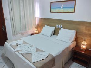 a bedroom with a large bed with white sheets at Arraial do Sol Beach Hotel in Arraial d'Ajuda