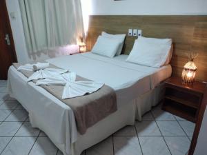 1 dormitorio con 1 cama grande con sábanas blancas en Arraial do Sol Beach Hotel, en Arraial d'Ajuda