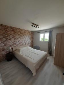 - une chambre avec un lit et un mur en briques dans l'établissement Domaine de Charoussas le mas de mon père, à Lagorce