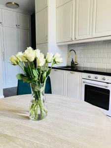 un jarrón de flores blancas sentado en una mesa en GOLD APARTMENT Piotrkowska 37, en Łódź