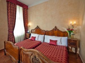 a bedroom with two beds with red and white pillows at Hotel Caesar Prague in Prague