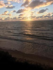 una puesta de sol en la playa con el océano en Kāpas, en Jūrkalne