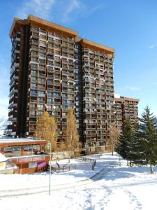 un grand bâtiment dans la neige devant un bâtiment dans l'établissement travelski home classic - Résidence Vanguard, au Corbier