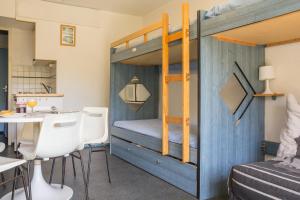 Cette chambre comprend des lits superposés, une table et des chaises. dans l'établissement travelski home classic - Résidence Vanguard, au Corbier