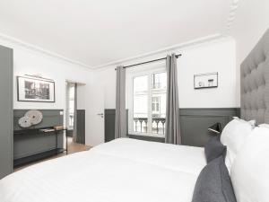 una camera con un letto bianco e una finestra di LivinParis - Luxury 3 Bedrooms Le Louvre II a Parigi