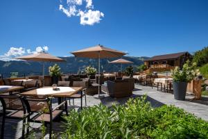 a restaurant with tables and chairs with mountains in the background at Das Grünholz Aparthotel in Mühlbach am Hochkönig +81 photos
