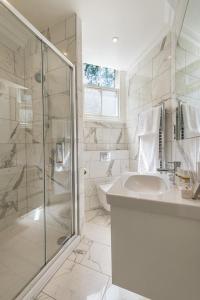 a white bathroom with a sink and a shower at Chelsea - Sloane Avenue by Viridian Apartments in London