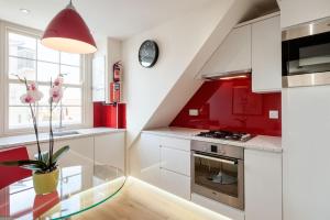 a kitchen with red and white cabinets and a glass table at Chelsea - Sloane Avenue by Viridian Apartments in London