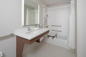 a white bathroom with a sink and a tub at Holiday Inn Express Seattle - Sea-Tac Airport, an IHG Hotel in SeaTac