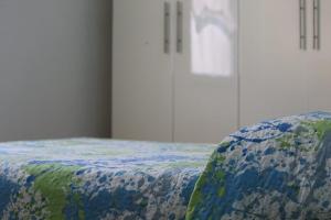 a bed with a blue and green comforter on it at Eleonora’s Home in Aosta