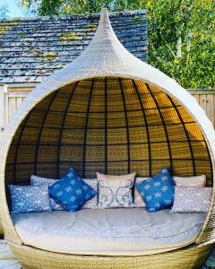 a wicker swing with pillows on a patio at Campden Mews in Chipping Campden