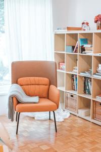 an orange chair in a room with a book shelf at Entoli Apartment in Podnanos