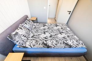 a bed with a black and white blanket on it at Apartament Piano Centrum in Racibórz