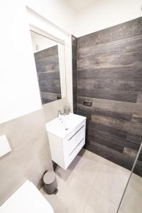 a bathroom with a white sink and wooden wall at Apartament Piano Centrum in Racibórz