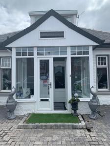 a white house with a large glass door at Peacock Guest House in Largs