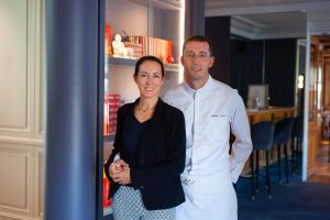 Un uomo e una donna in piedi accanto a un frigorifero di Hotel d'Angleterre a Chalons en Champagne