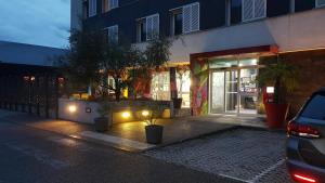 uma frente de loja à noite com luzes numa rua em Ekho Hotel Grenoble Nord Saint Egrève em Saint-Égrève