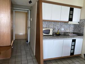 a kitchen with white cabinets and a microwave at Heliodoro Flat Golden Beach in Recife