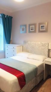 a bedroom with a white bed with a dresser and a window at Edinburgh City Holiday Apartments in Edinburgh