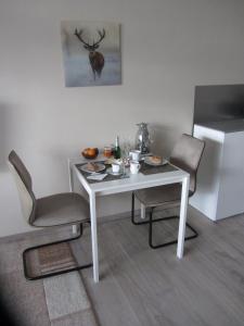 une table blanche avec deux chaises et un réfrigérateur blanc dans l'établissement Appartement Ausblick, à Hahnenklee