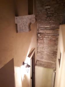 un pasillo con una pared de piedra y una luz en la pared en Residenza La Luce di Assisi, en Asís