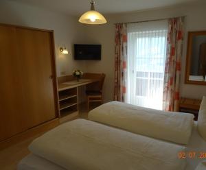 ein Hotelzimmer mit 2 Betten, einem Schreibtisch und einem Fenster in der Unterkunft Gästehaus Maria in Kartitsch