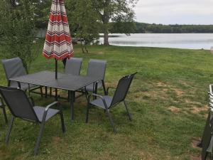 uma mesa e cadeiras com um guarda-sol e um lago em Reel Simple Bolton Lake Cottage em Bolton