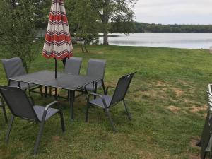 a table and chairs with an umbrella and a lake at Reel Simple Bolton Lake Cottage in Bolton