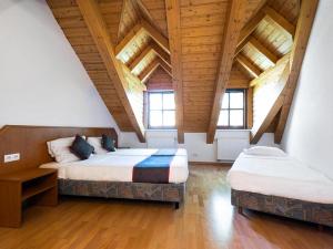 two beds in a room with wooden ceilings and windows at Hotel Bohemia in Berlin