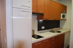 La cocina está equipada con nevera blanca y armarios de madera. en Apartamento Garona, en Vielha