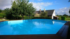 uma grande piscina azul em frente a uma casa em Les Gages em Brécé