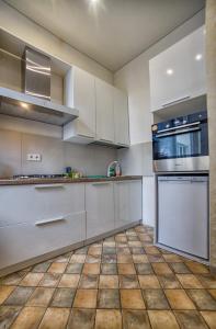 a kitchen with white cabinets and a tiled floor at Apartment on Kommunisticheskaya in Smolensk