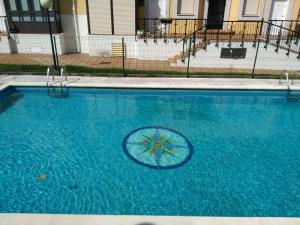 a blue swimming pool with an umbrella in the water at Apartamento LA FRAGUA in Comillas