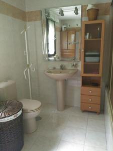 y baño con lavabo, aseo y espejo. en APARTAMENTO CON PISCINA, en Comillas