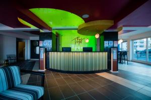 a lobby with a bar with a green wall at The Tryst Beachfront Hotel in San Juan